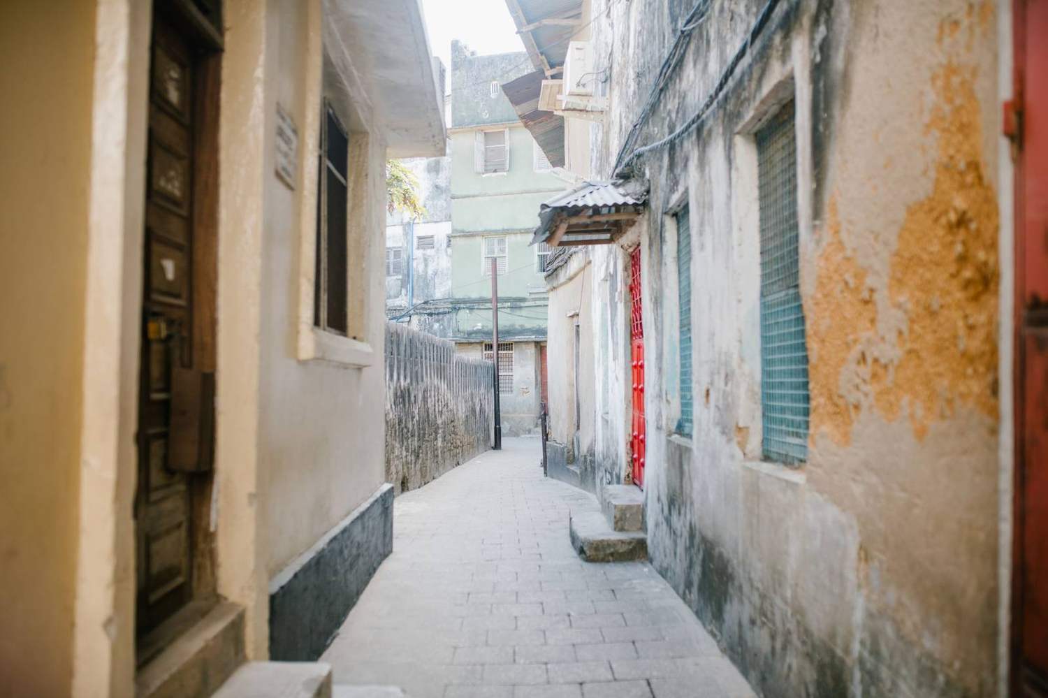A narrow historic lane in Stone Town, Zanzibar, with carved doors and coral-stone walls